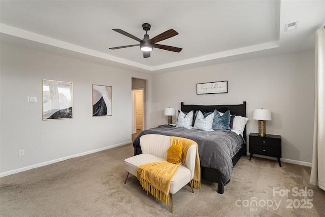 carpeted bedroom featuring a raised ceiling and ceiling fan