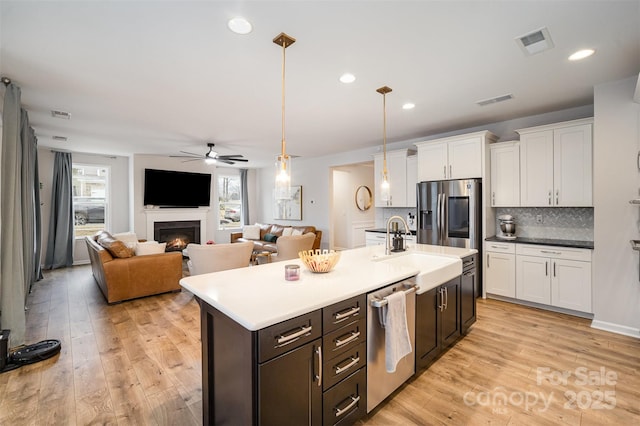 kitchen with stainless steel appliances, white cabinets, light hardwood / wood-style floors, and decorative light fixtures