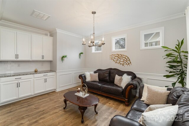 living room featuring crown molding, a chandelier, and light hardwood / wood-style floors