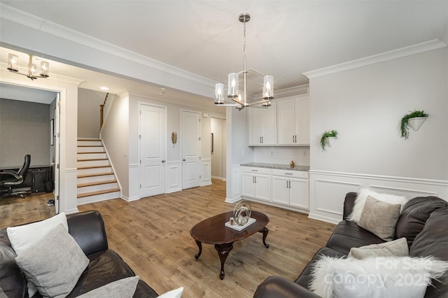 living room featuring an inviting chandelier, crown molding, and light hardwood / wood-style floors