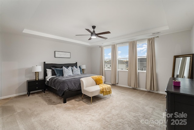 carpeted bedroom featuring a raised ceiling and ceiling fan