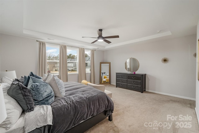 carpeted bedroom featuring ceiling fan and a raised ceiling