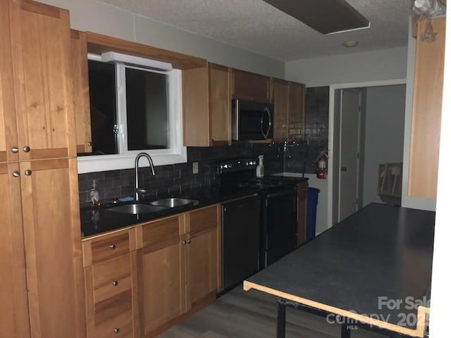 kitchen with tasteful backsplash, sink, black appliances, and hardwood / wood-style floors