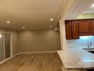 interior space with a sink, wood finished floors, recessed lighting, and light countertops