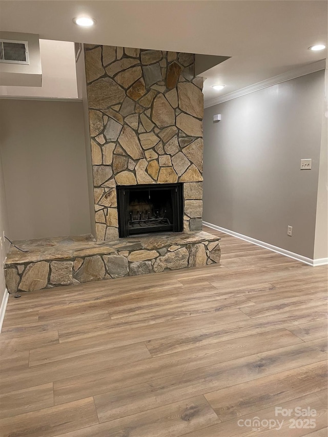 interior space with visible vents, crown molding, baseboards, a fireplace, and wood finished floors