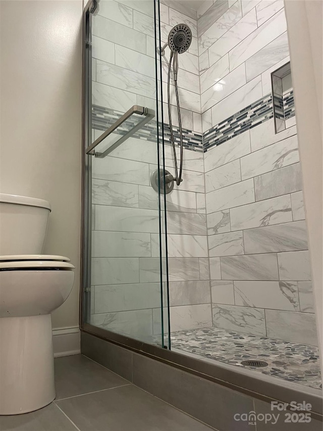 bathroom featuring toilet and a shower stall