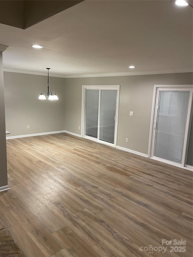 empty room featuring wood finished floors, baseboards, recessed lighting, ornamental molding, and a chandelier