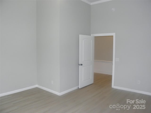 empty room with crown molding and light hardwood / wood-style floors