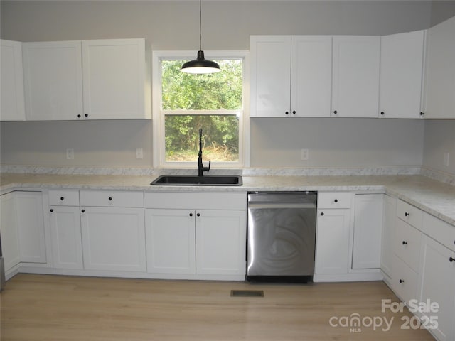 kitchen with pendant lighting, sink, stainless steel dishwasher, and white cabinets