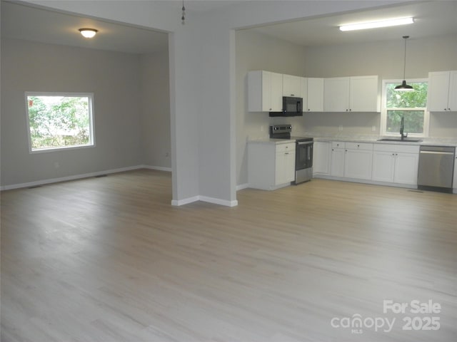 kitchen featuring sink, white cabinetry, decorative light fixtures, appliances with stainless steel finishes, and light hardwood / wood-style floors