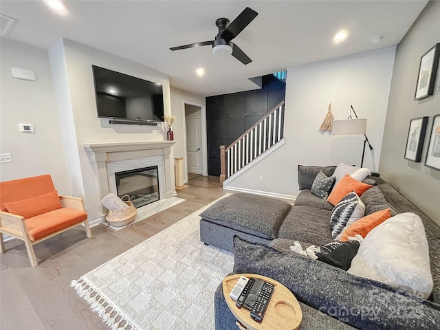 living room with hardwood / wood-style floors, a high end fireplace, and ceiling fan