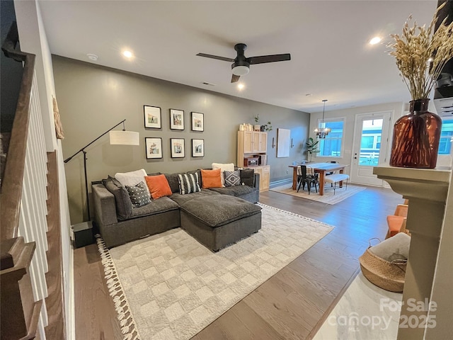 living room featuring ceiling fan with notable chandelier and light hardwood / wood-style floors