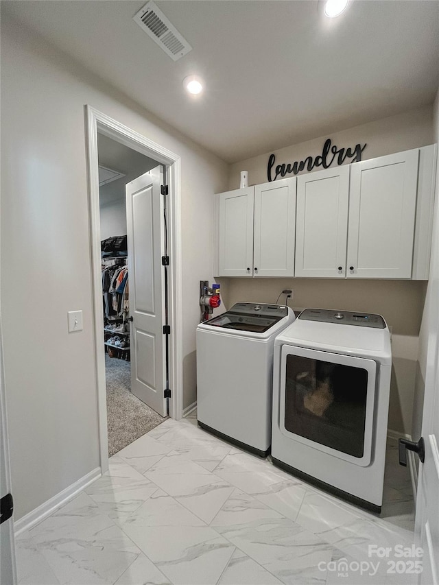 clothes washing area with cabinets and washing machine and clothes dryer