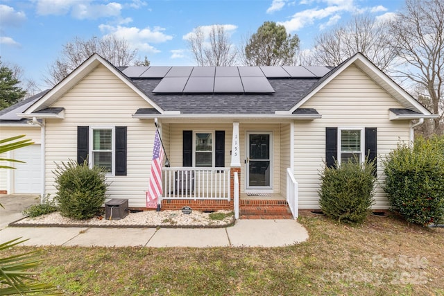 ranch-style home featuring a garage, a front yard, covered porch, and solar panels