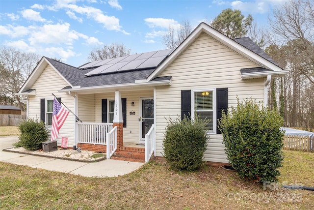 bungalow-style home featuring a porch, a front lawn, and solar panels