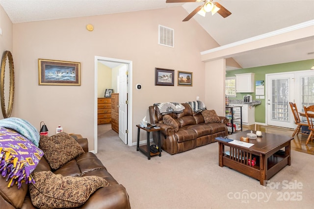 carpeted living room with ceiling fan, high vaulted ceiling, and a healthy amount of sunlight