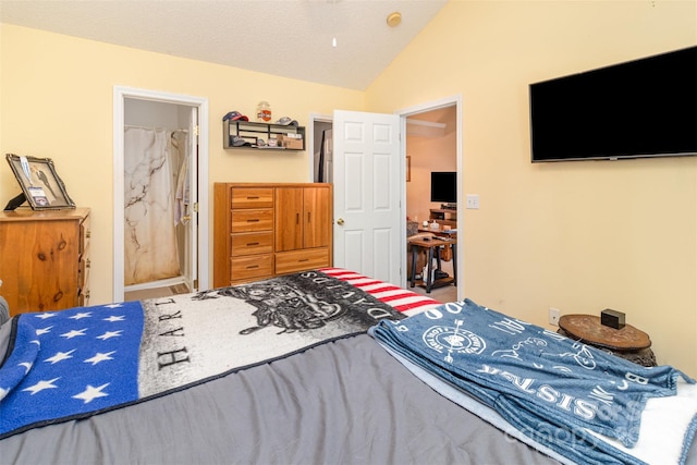 bedroom with connected bathroom, vaulted ceiling, and a textured ceiling