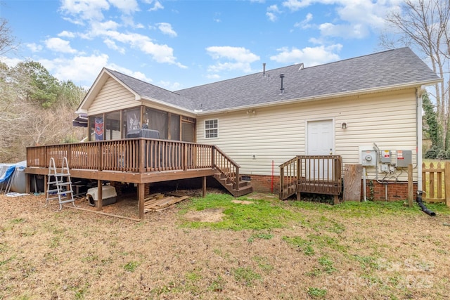 back of property with a wooden deck, a sunroom, and a yard