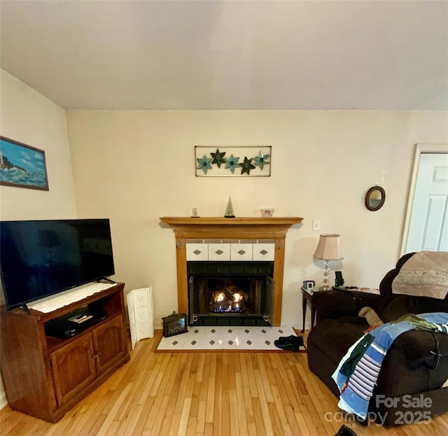 living room featuring a tiled fireplace and light wood-type flooring