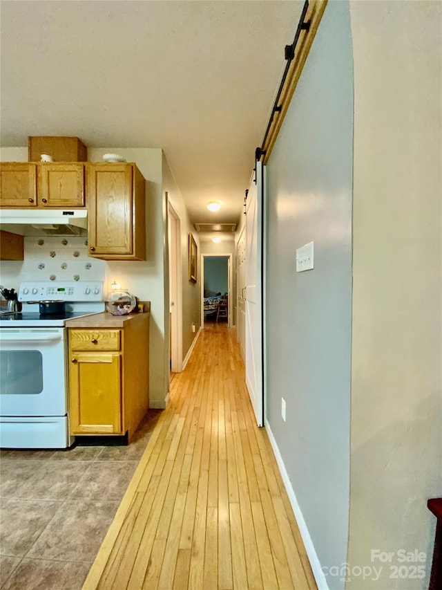 kitchen featuring light hardwood / wood-style flooring, a barn door, and white electric range oven