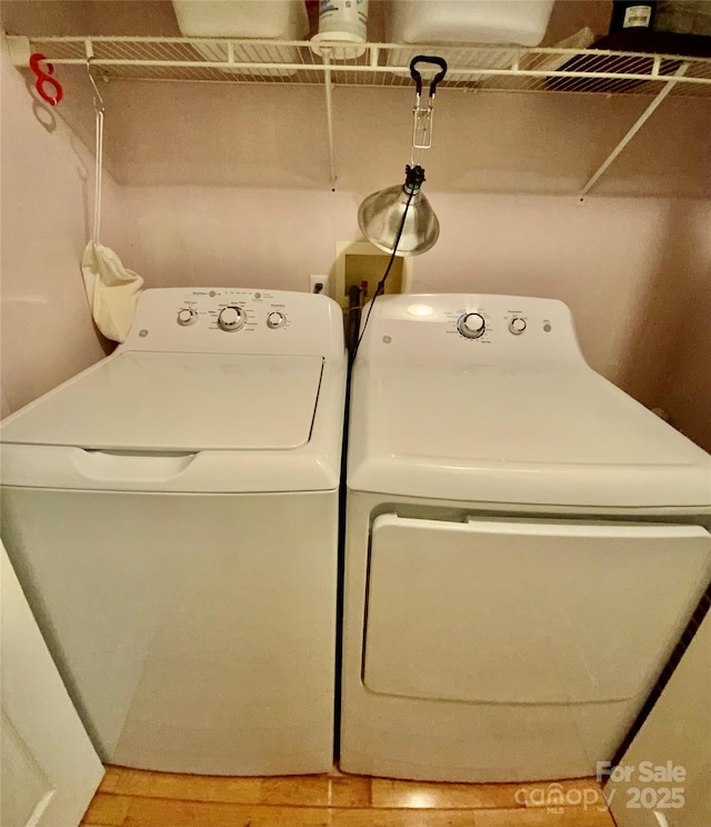 clothes washing area with hardwood / wood-style floors and independent washer and dryer