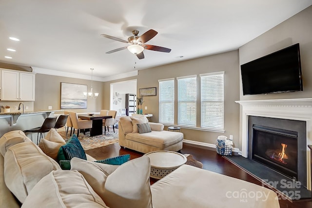 living room featuring ceiling fan with notable chandelier, dark hardwood / wood-style floors, and sink