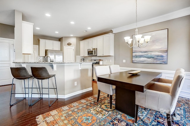 dining area featuring ornamental molding, dark hardwood / wood-style floors, a chandelier, and sink