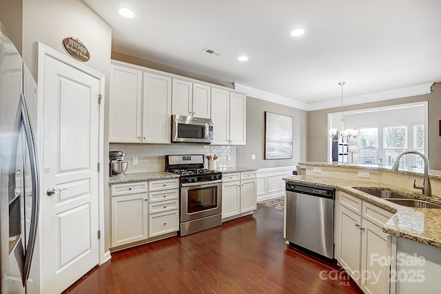 kitchen featuring sink, hanging light fixtures, ornamental molding, stainless steel appliances, and light stone countertops