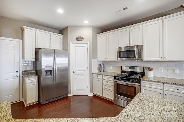 kitchen with light stone countertops, dark wood-type flooring, stainless steel appliances, and white cabinets