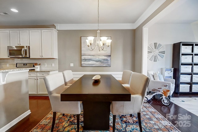 dining area with dark hardwood / wood-style flooring, crown molding, and an inviting chandelier