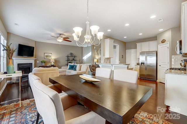 dining area with dark hardwood / wood-style flooring and ceiling fan with notable chandelier