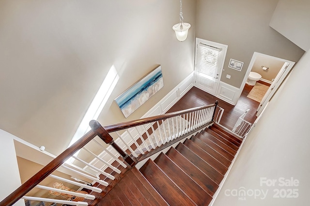 staircase with a towering ceiling and wood-type flooring