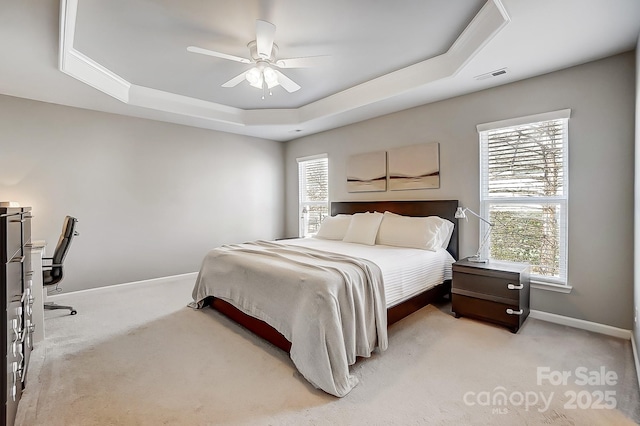 carpeted bedroom featuring ceiling fan and a tray ceiling