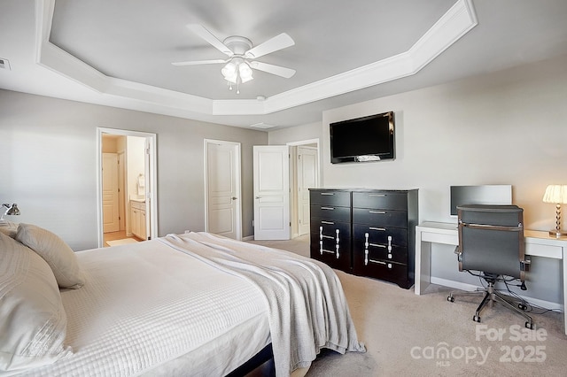 bedroom with a raised ceiling, light colored carpet, ceiling fan, and ensuite bath