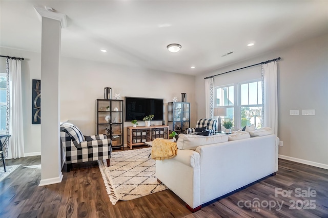 living room with decorative columns and dark wood-type flooring