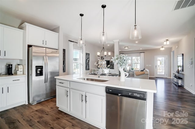 kitchen featuring sink, white cabinetry, a kitchen island with sink, stainless steel appliances, and decorative light fixtures