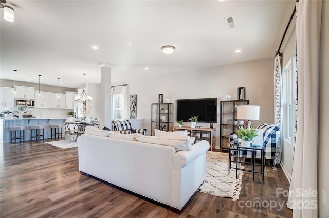 living room with a chandelier, hardwood / wood-style floors, and decorative columns