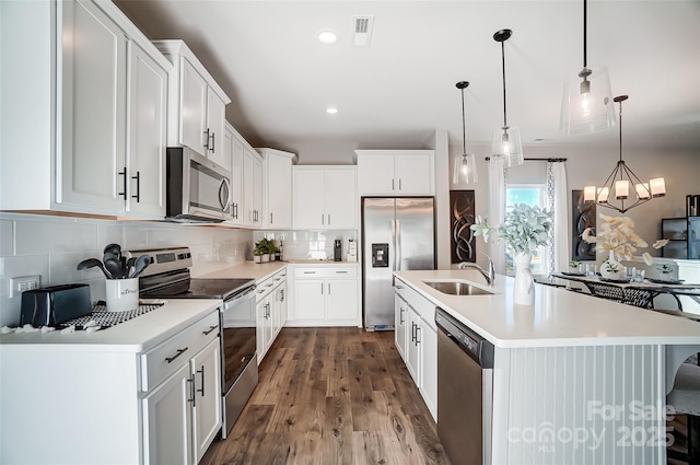 kitchen featuring sink, white cabinetry, hanging light fixtures, a center island with sink, and stainless steel appliances