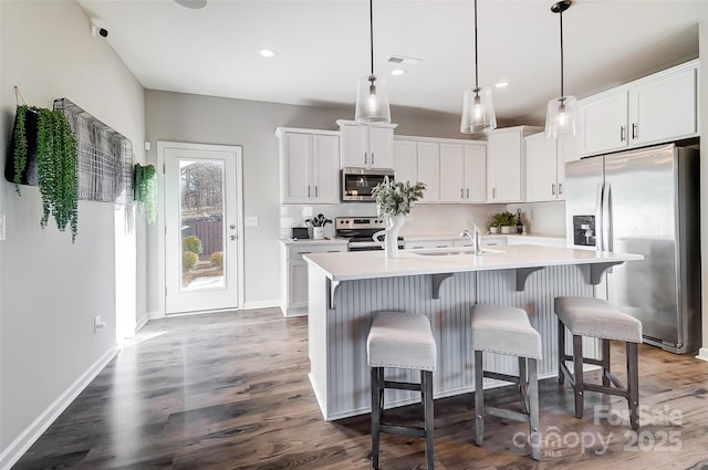 kitchen featuring white cabinetry, sink, stainless steel appliances, and an island with sink