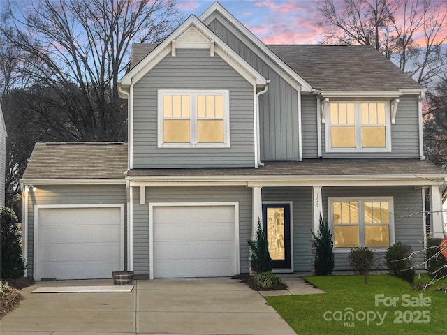 view of front of property with a shingled roof, concrete driveway, board and batten siding, covered porch, and a front yard