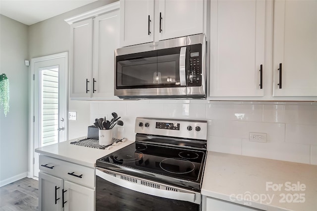 kitchen with white cabinets, tasteful backsplash, appliances with stainless steel finishes, and light wood-style flooring