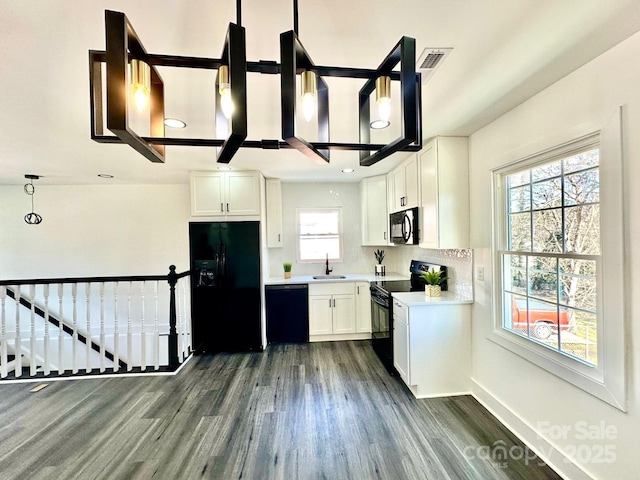 kitchen featuring dark hardwood / wood-style floors, pendant lighting, sink, white cabinets, and black appliances