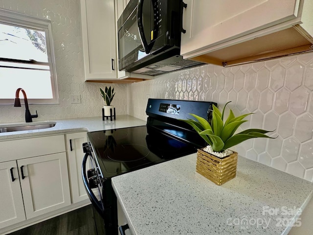 kitchen with light stone counters, white cabinetry, sink, and black appliances