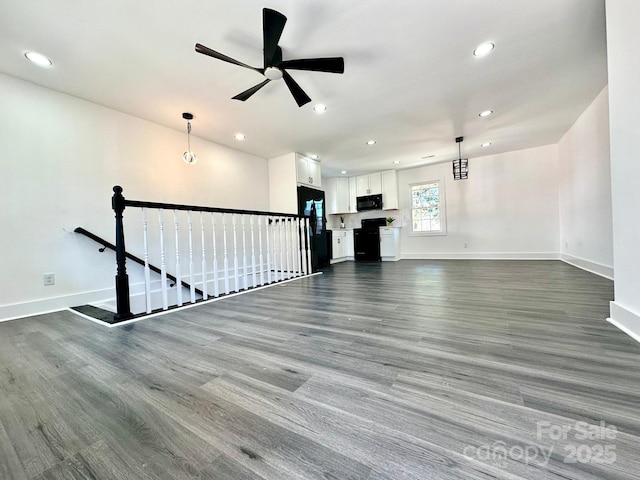 unfurnished living room with dark hardwood / wood-style flooring and ceiling fan