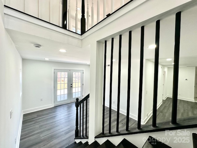 stairs with hardwood / wood-style floors, a towering ceiling, and french doors