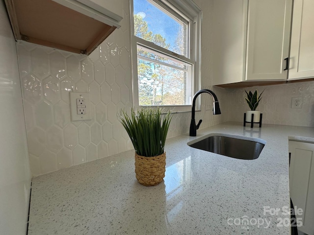 kitchen featuring light stone countertops, sink, and white cabinets