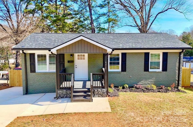 view of front facade with brick siding, a front yard, and a shingled roof