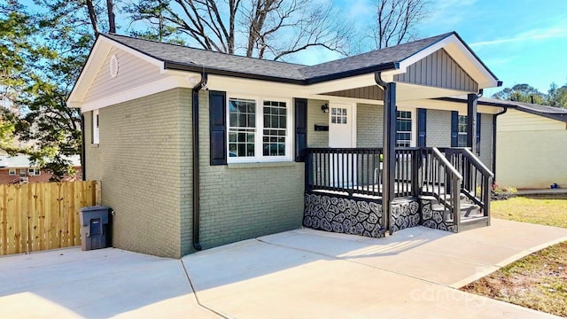 view of front of home with a porch, fence, and brick siding