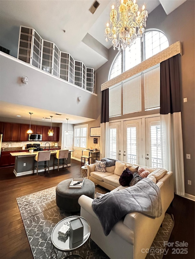 living room with baseboards, dark wood-style floors, an inviting chandelier, and visible vents