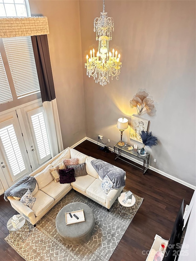 unfurnished living room with a notable chandelier, baseboards, and wood finished floors